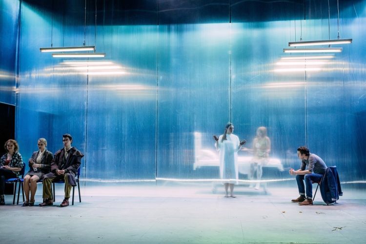 Waiting room style set with actors sitting on chairs